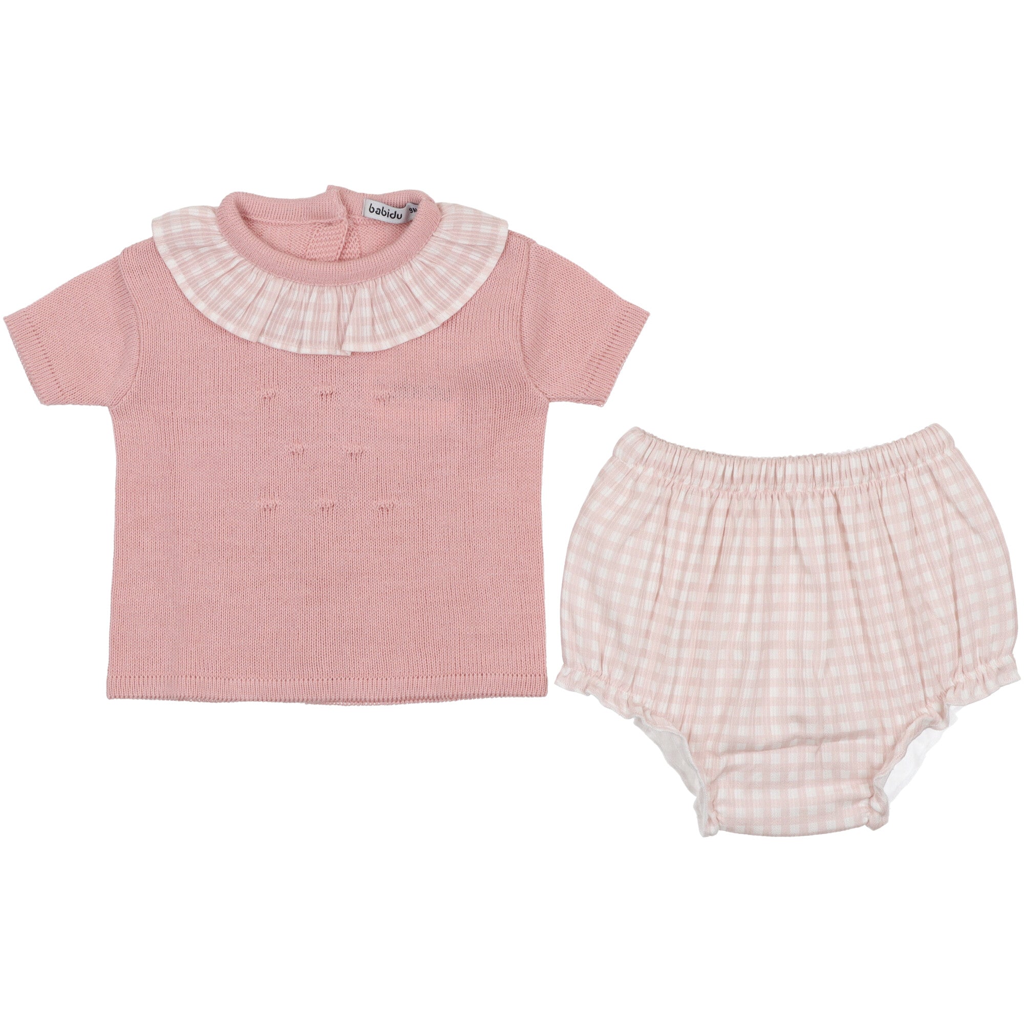 maglia-coulotte in cotone. La maglia a maniche a mezza lunghezza, collo rotondo con volant e superficie lavorata con motivo in rilievo. Chiusura posteriore mediante bottoni. La coulotte in cotone vichy rosa foderata è rifinita con morbido elastico