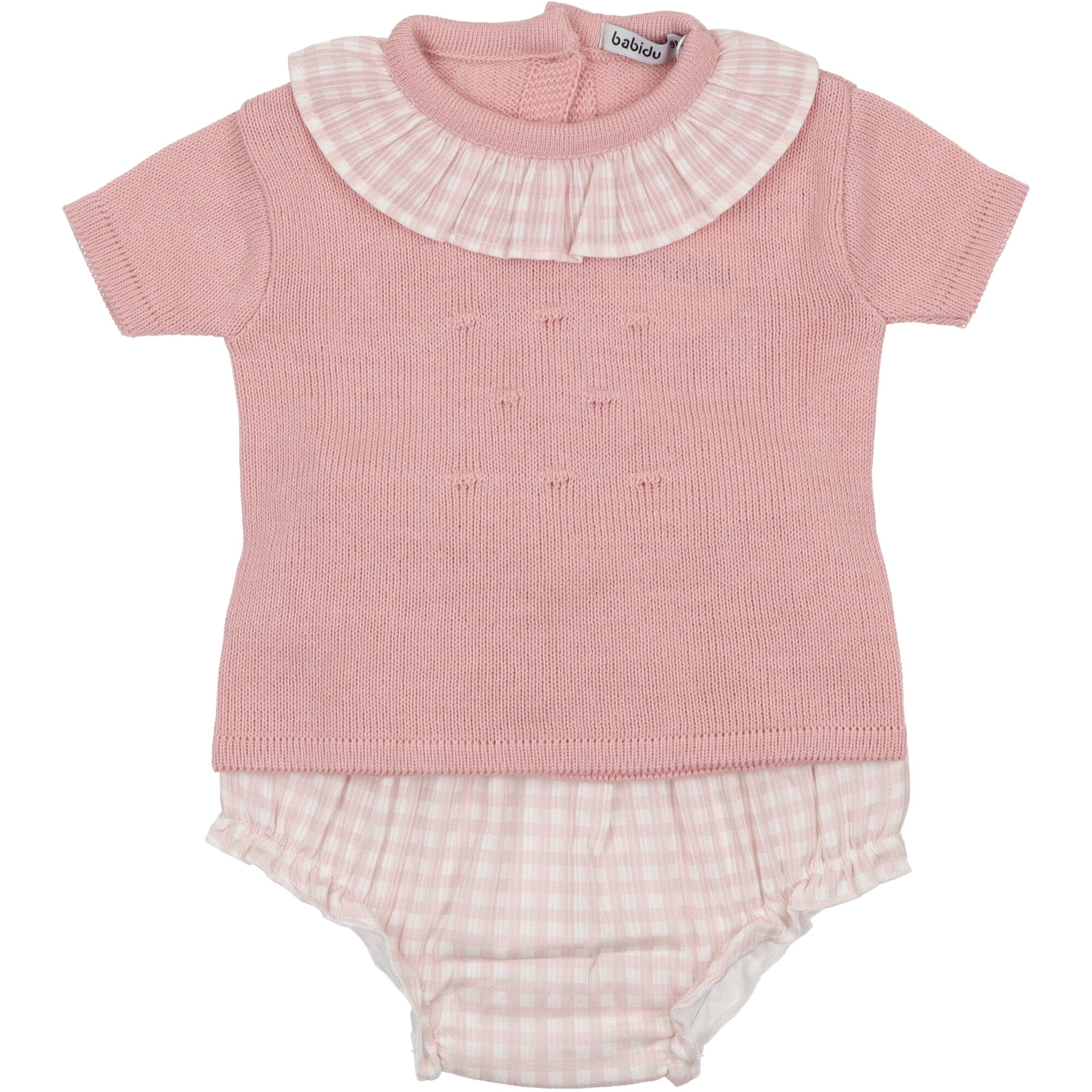 maglia-coulotte in cotone. La maglia a maniche a mezza lunghezza, collo rotondo con volant e superficie lavorata con motivo in rilievo. Chiusura posteriore mediante bottoni. La coulotte in cotone vichy rosa foderata è rifinita con morbido elastico